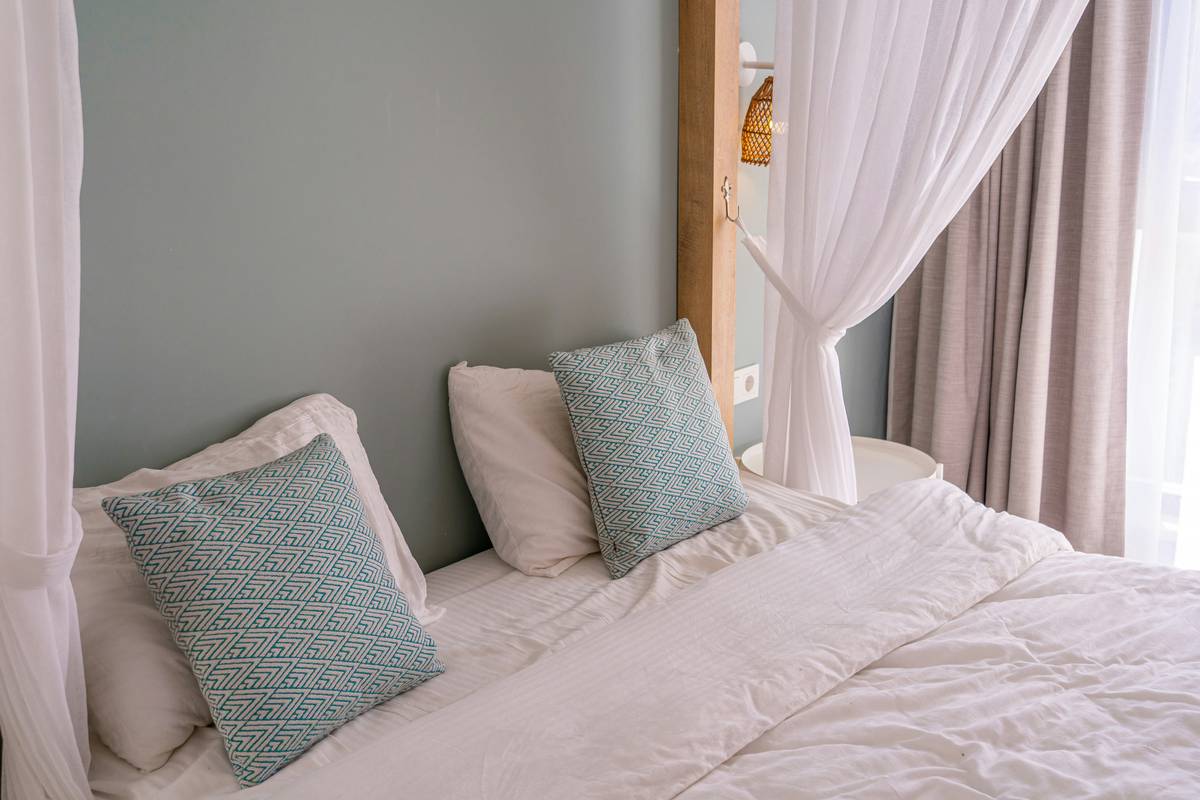 tips for improving your sleep quality shown through a serene bedroom scene with blackout curtains, cool temperature, and no electronics