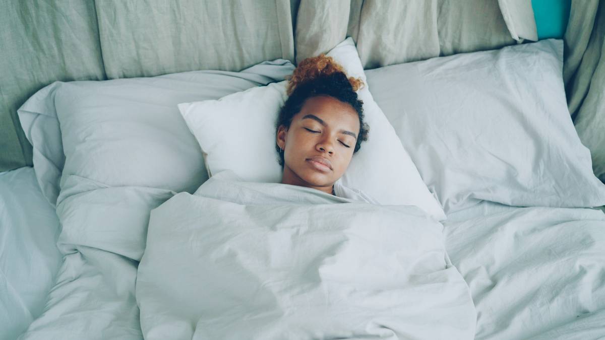 Person practicing sleep create routine by reading a book beside dim lamp with phone on airplane mode
